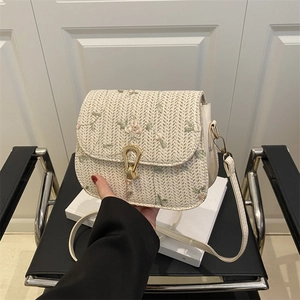 Beige woven straw crossbody bag with floral embroidery and golden metal clasp closure