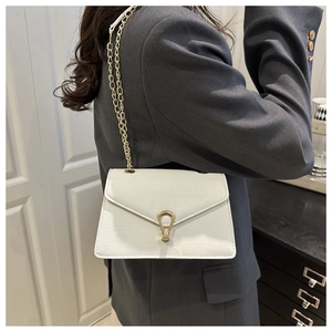 Detail of white crocodile pattern chain bag with golden clasp and shoulder strap
