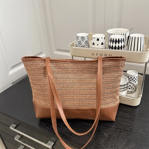 Woven straw tote bag with brown leather handles and chevron pattern for beach or daily use