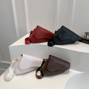 Chic woven saddle bags in red, black, white, and brown on a minimalist display