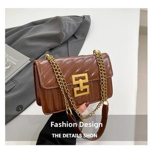 Detail of glossy brown quilted leather with golden metal chain strap and square buckle