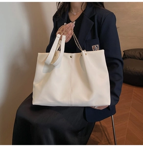 Minimalist beige tote bag shown on a model featuring fine texture and gold chain strap