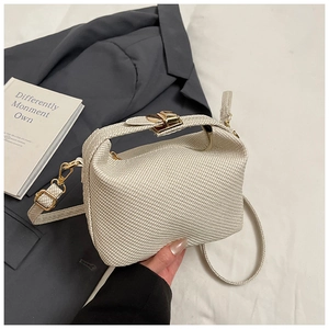 Detail of cream woven handbag with gold hardware and textured pleated structure