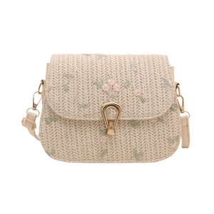 Straw crossbody bag with floral embroidery and gold horseshoe buckle on white background
