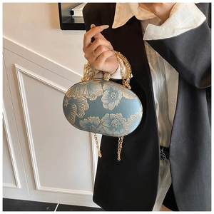 Detail of elegant grey-blue evening bag with golden floral embroidery and sphere clasp