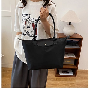 Détail du grand sac cabas en nylon noir avec anses en cuir et fermeture par bouton doré
