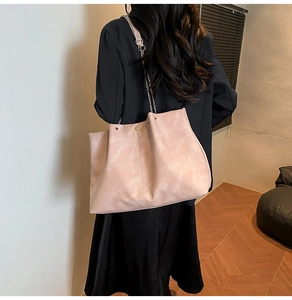 Detail view of large tote bag with chain strap shown on model in a modern home setting