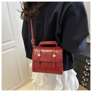 Detail of red vintage square handbag with leather texture and gold stud accents
