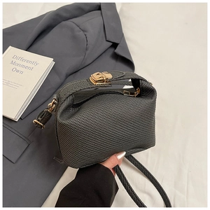 Close-up of black textured pillow bag with gold clasp and top handle for women