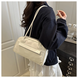 Elegante borsa bowling color crema con finitura lucida indossata da una modella