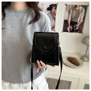 Detailed view of black quilted faux leather crossbody bag with snap closure and long strap