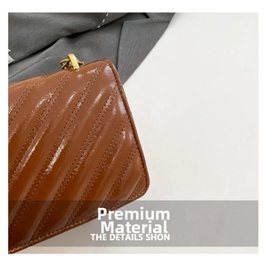 Detailed macro view of the glossy brown leather with quilted diamond patterns and gold chain