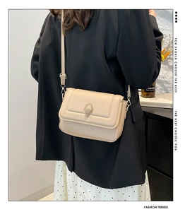 Detailansicht der beige Umhängetasche mit goldenem Adleremblem und Trageriemen
