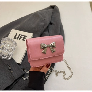 Detail of pink mini crossbody bag with silver bow ornament and elegant metal chain strap