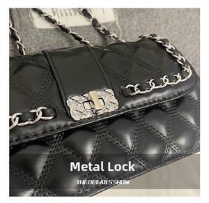 Detail of black quilted leather shoulder bag featuring silver chain strap and metal clasp