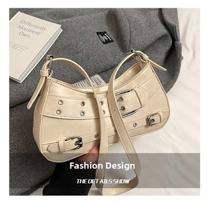 Detail of beige punk crossbody bag featuring silver metal buckles and eyelet hardware