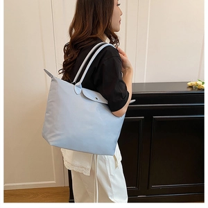 Détail d'un sac cabas en nylon bleu clair avec longues anses et rabat à boucle métallique