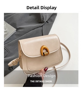 Detail of cream saddle bag featuring a gold horseshoe metal buckle and leather texture