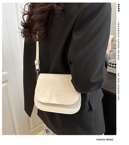 Detail view of cream saddle bag with cracked marble texture and fashion slogan print