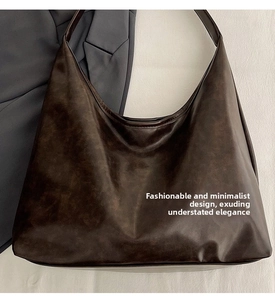 Detail of dark brown tote bag showing matte texture and wide shoulder strap design