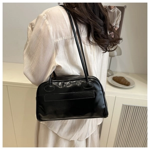 Dettaglio di una borsa a spalla in pelle nera lucida con sottili doppie tracolle