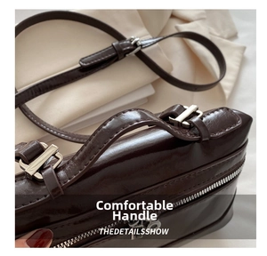 Detail of dark brown glossy leather handbag with silver zipper and adjustable strap