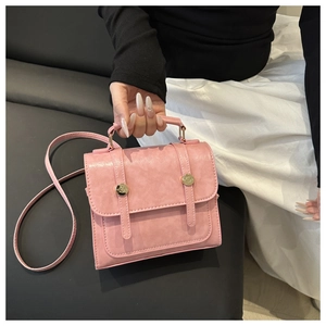Detail of pink textured faux leather handbag showing top handle and gold hardware