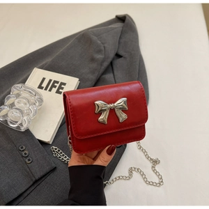 Detailed view of red PU handbag with silver metal bow and elegant chain strap