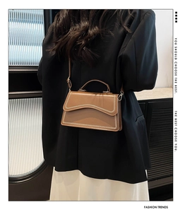 Brown leather crossbody bag with decorative V-shaped stitching shown on model