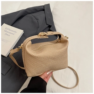 Detail of light beige woven mini pillow bag with gold metal lock and long strap
