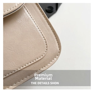 Close-up of beige leather saddle bag with refined texture and neat white stitching