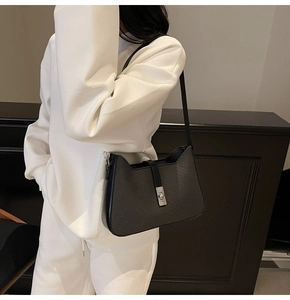 Detailed close-up of a black textured underarm bag featuring a silver square metal buckle