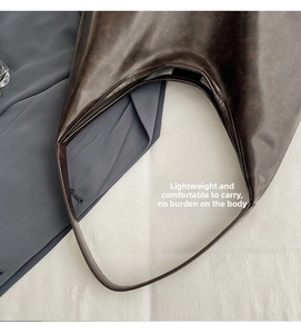 Close-up of vintage dark brown faux leather texture and wide strap of the tote bag