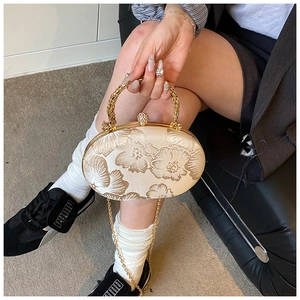 Detail of embroidered floral evening bag with golden metal frame and diamond clasp