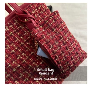 Macro detail of red and gold tweed fabric texture with a matching small coin purse charm