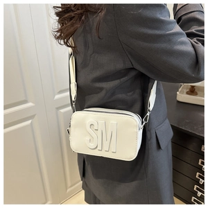 Dettaglio della borsa fotografica bianca in pelle con logo SM e tracolla larga