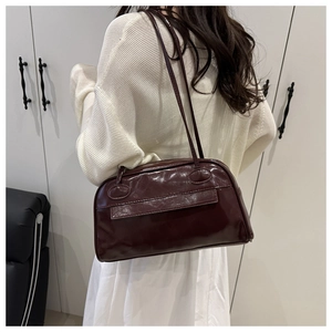 Dettaglio della texture in pelle lucida bordeaux e cuciture della borsa bowling