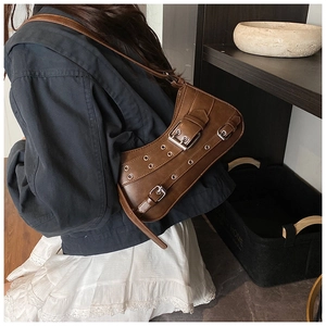 Close-up of brown vintage Y2K hobo bag with metal grommets and buckle details worn on shoulder