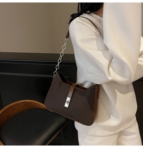 Detail of dark brown textured leather shoulder bag featuring silver metal twist lock
