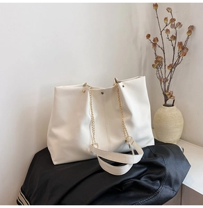 Detail of white tote bag showing premium pebble leather texture and gold chain strap