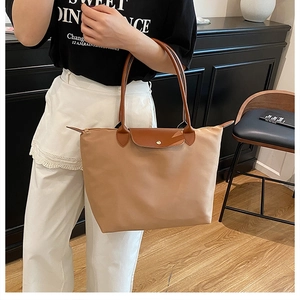 Détail du sac cabas en nylon avec rabat en cuir et doubles poignées de transport renforcées