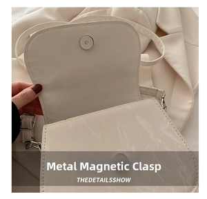 Detailed view of the metallic magnetic closure and fine stitching on a cream saddle bag