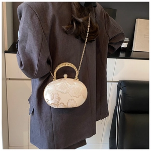Close-up of white satin evening bag with floral embroidery and gold metal handle