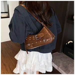 Detail view of vintage brown underarm bag with decorative buckle straps on model
