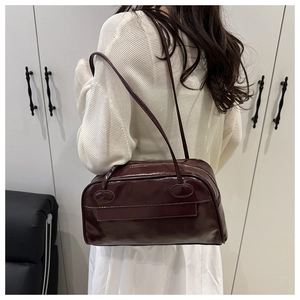 Modello con borsa bowling lucida bordeaux scuro con tracolle lunghe e design capiente