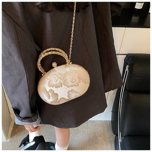 Detail of champagne evening bag with floral embroidery and gold metal handle