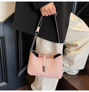 Detalle de bolso en cuero sarga rosa con cadena de metal plateado y hebilla decorativa