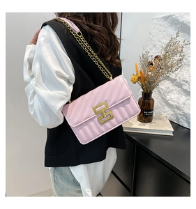 Detail view of pink quilted handbag featuring a gold H-lock and chain shoulder strap