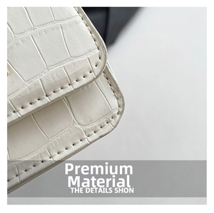 Détail rapproché de la texture crocodile blanche avec surpiqûres noires sur un sac à main