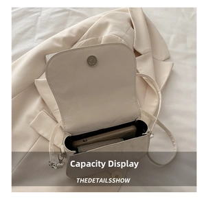 Internal capacity of the cream crossbody saddle bag showing fit for a smartphone